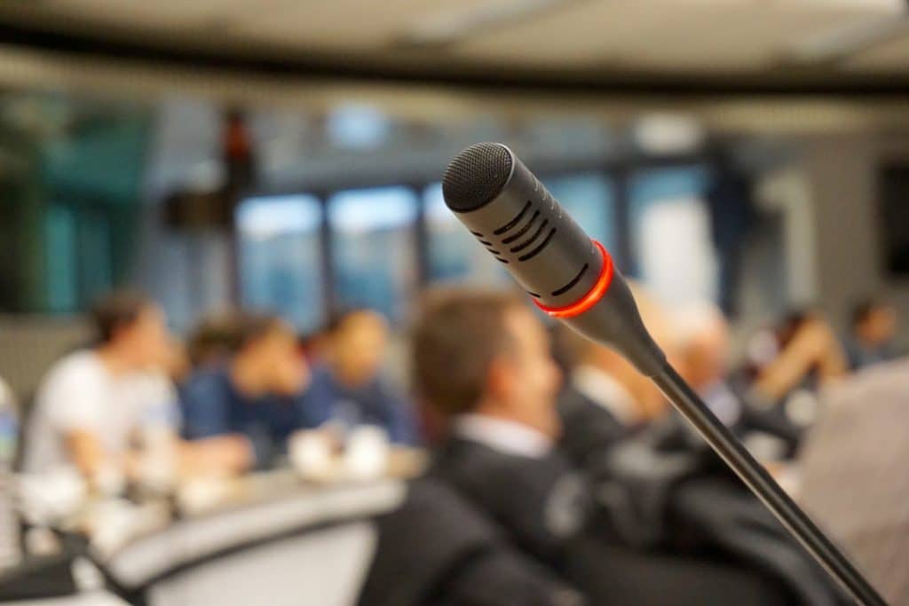 people at a conference with mic in foreground